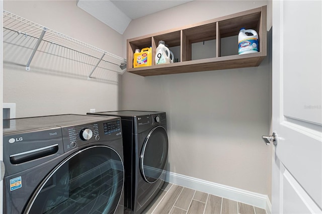 clothes washing area featuring baseboards, laundry area, wood tiled floor, and washer and dryer