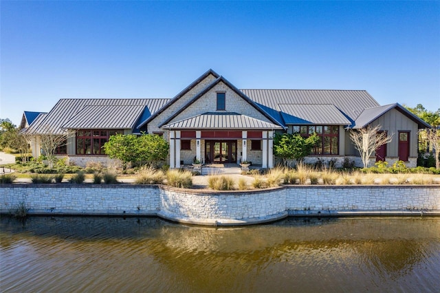 back of property featuring a water view, a standing seam roof, and metal roof