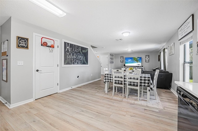 dining space featuring a textured ceiling and light hardwood / wood-style flooring