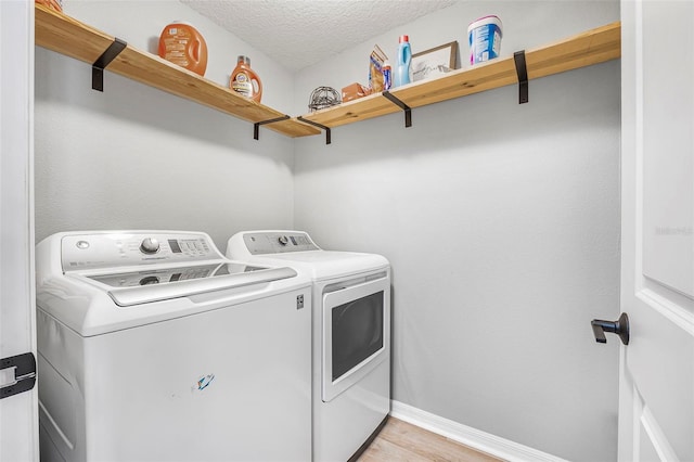 laundry room with light hardwood / wood-style flooring, independent washer and dryer, and a textured ceiling