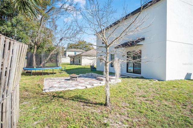 view of yard featuring a patio, a trampoline, and an outdoor fire pit