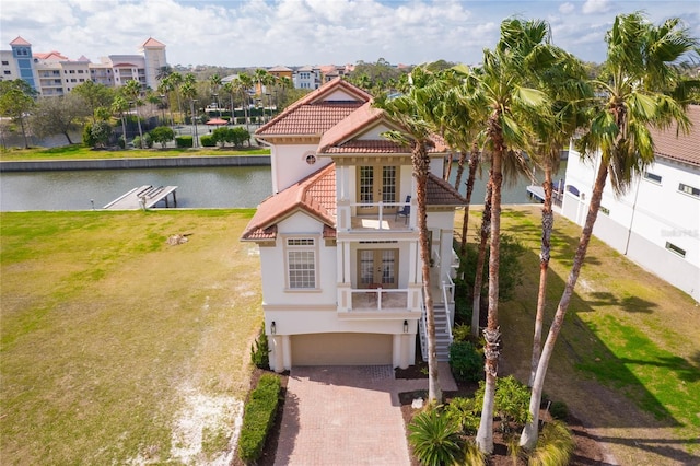 mediterranean / spanish-style house with a water view, a garage, a front lawn, and french doors