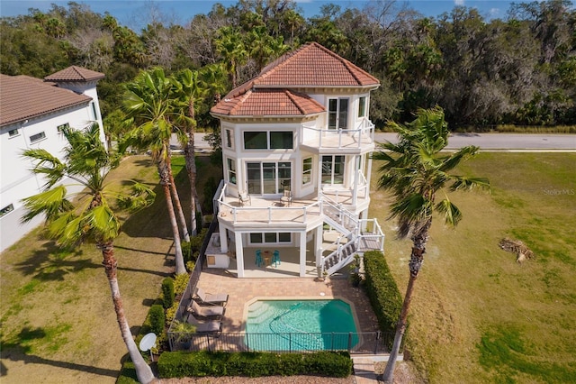 rear view of property featuring a fenced in pool, a balcony, and a patio area