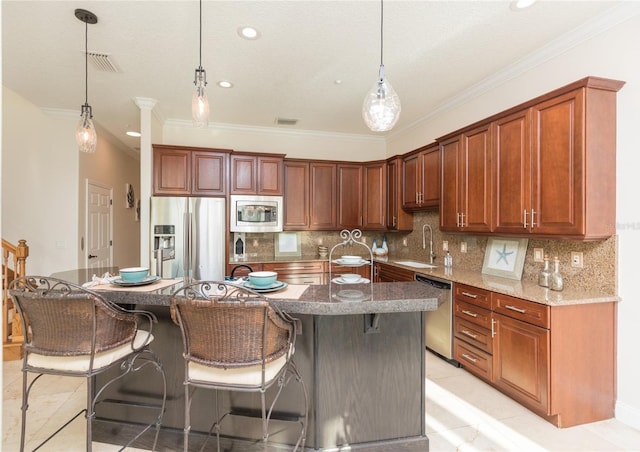 kitchen featuring stainless steel appliances, a kitchen breakfast bar, sink, and hanging light fixtures