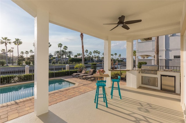 view of pool featuring an outdoor kitchen, a grill, ceiling fan, and a patio area