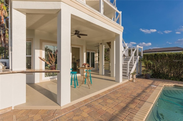 view of patio with a fenced in pool, a balcony, and ceiling fan