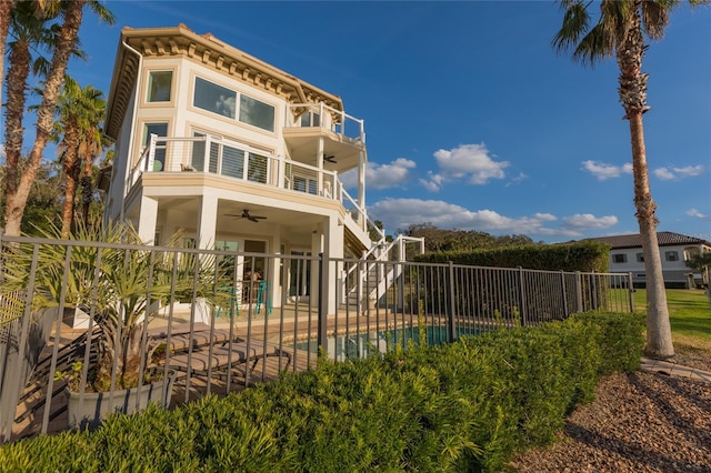 rear view of property featuring a fenced in pool, a balcony, a patio, and ceiling fan