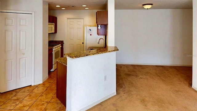 kitchen with light tile patterned flooring, sink, dark stone countertops, kitchen peninsula, and white appliances