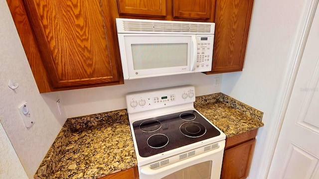 kitchen with dark stone countertops and white appliances