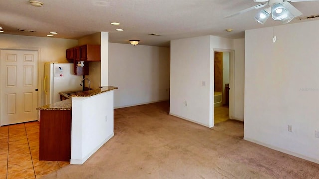 kitchen with sink, ceiling fan, white refrigerator, light colored carpet, and kitchen peninsula