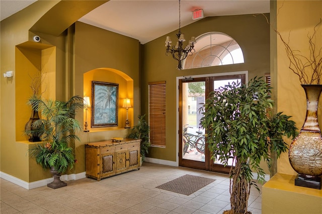 foyer featuring light tile patterned flooring, vaulted ceiling, an inviting chandelier, and french doors