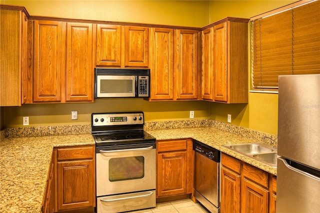 kitchen with appliances with stainless steel finishes, light stone countertops, sink, and light tile patterned floors