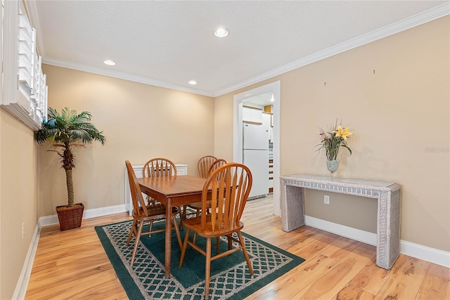 dining space featuring light wood-style floors, baseboards, and ornamental molding