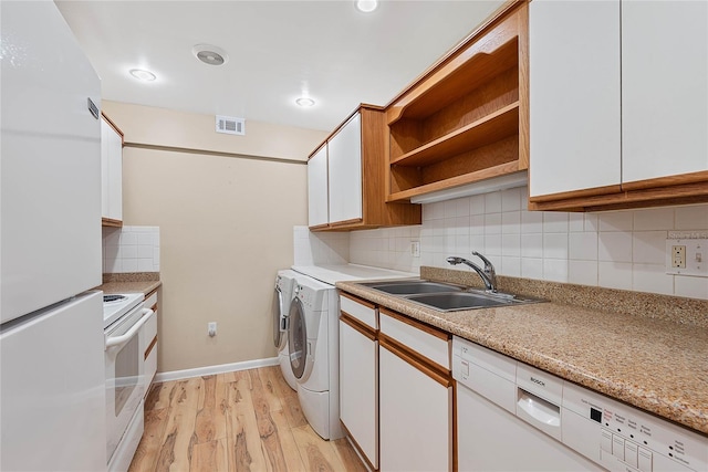 clothes washing area with laundry area, visible vents, independent washer and dryer, light wood-style floors, and a sink