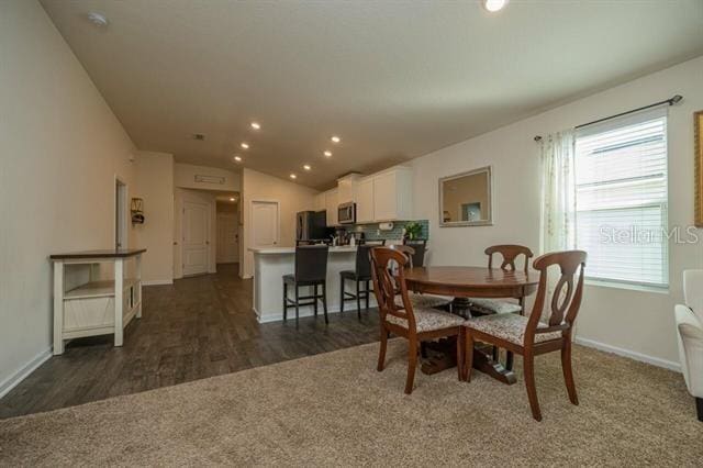 dining room featuring lofted ceiling and dark wood-type flooring