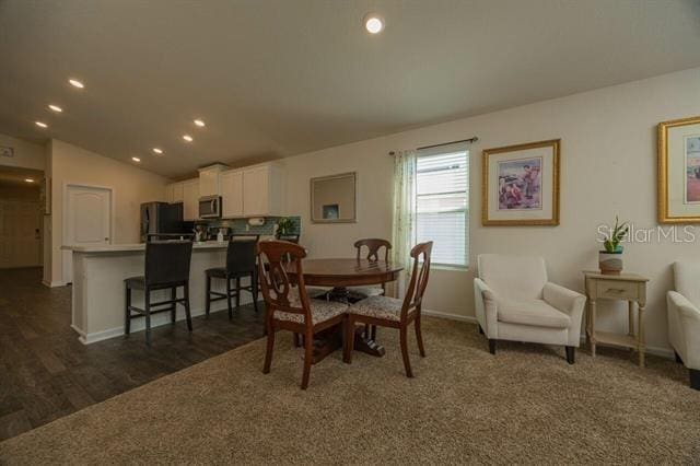 carpeted dining area featuring lofted ceiling