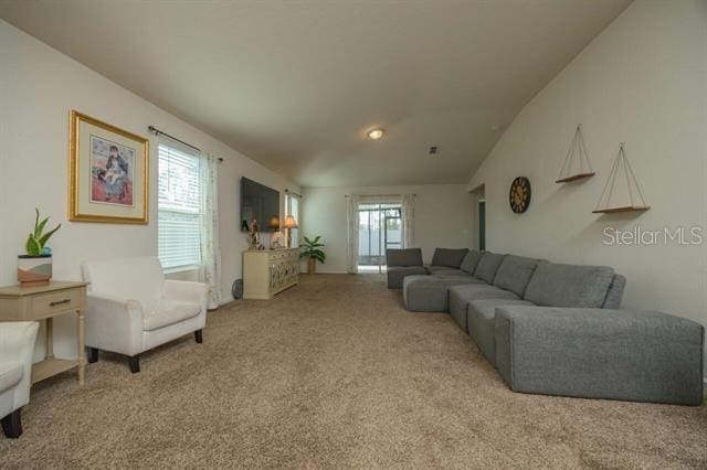 carpeted living room featuring vaulted ceiling