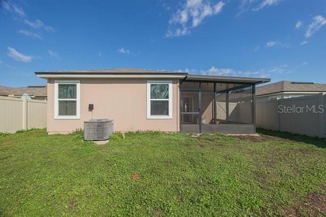 rear view of house with cooling unit, a yard, and a sunroom