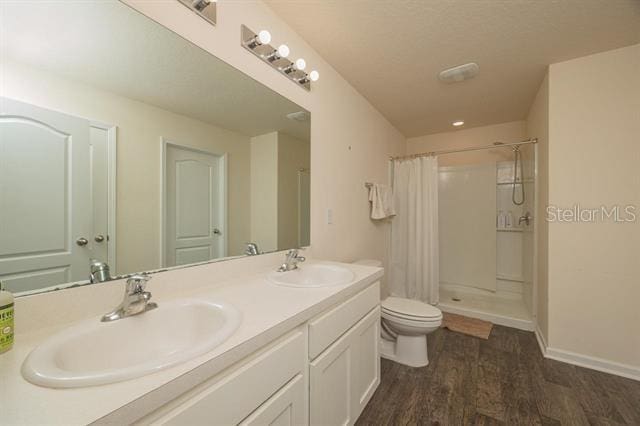 bathroom with wood-type flooring, toilet, a shower with shower curtain, and vanity