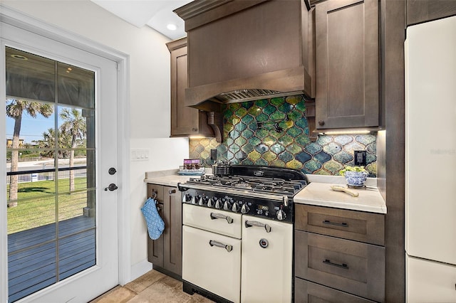 kitchen featuring dark brown cabinetry, backsplash, custom exhaust hood, and white refrigerator