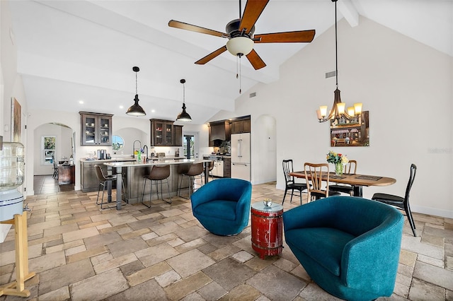 living room with high vaulted ceiling, beam ceiling, and ceiling fan with notable chandelier