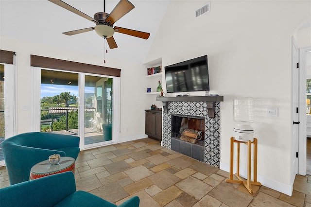 living room featuring ceiling fan, a fireplace, and high vaulted ceiling