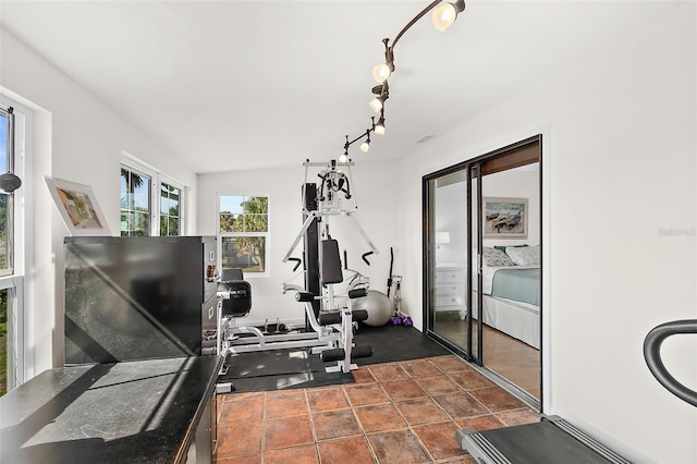 exercise area featuring dark tile patterned flooring and rail lighting