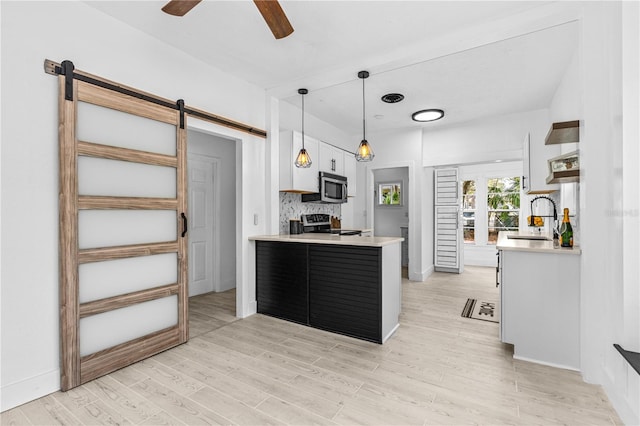 kitchen featuring pendant lighting, sink, appliances with stainless steel finishes, white cabinetry, and a barn door