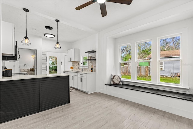 kitchen featuring white cabinetry, sink, decorative light fixtures, and light wood-type flooring