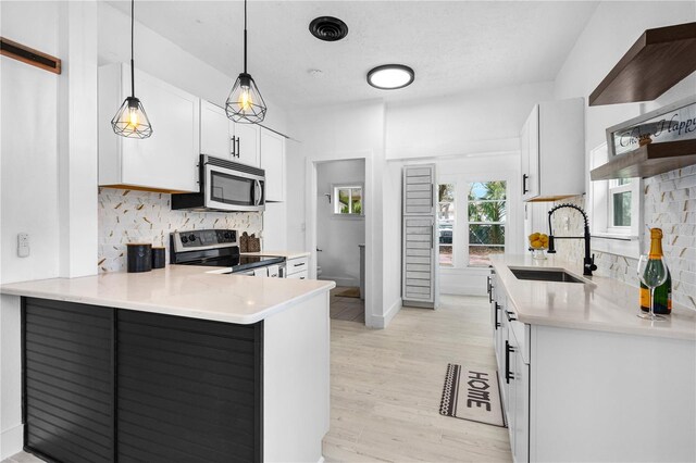 kitchen with pendant lighting, sink, white cabinets, kitchen peninsula, and stainless steel appliances
