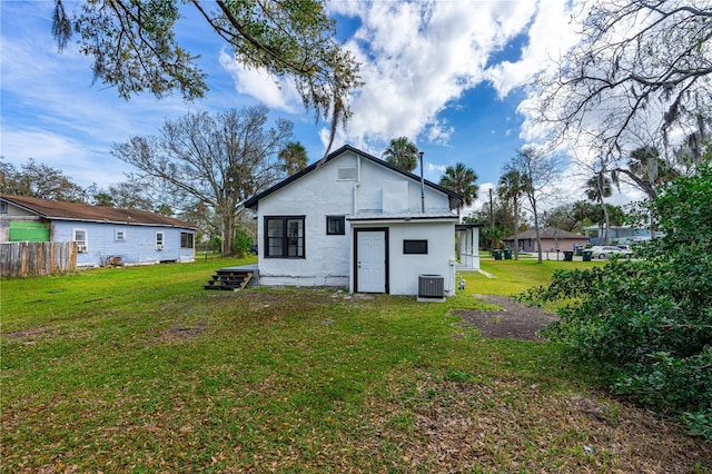 back of house featuring central AC unit and a yard