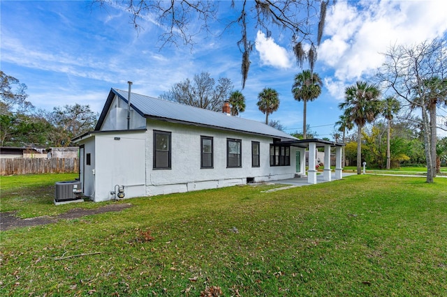 rear view of house with a yard and central AC