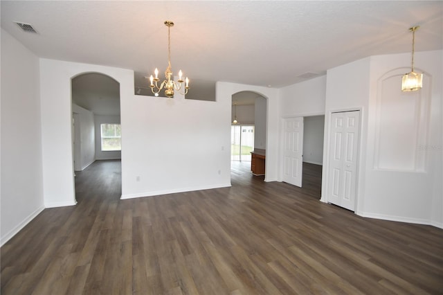 unfurnished room featuring visible vents, arched walkways, dark wood finished floors, and baseboards