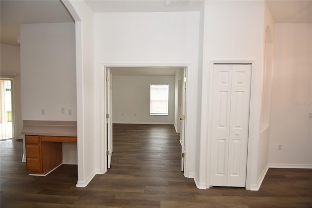 hallway featuring baseboards, arched walkways, and dark wood finished floors