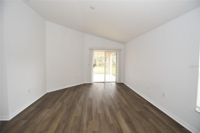 empty room featuring lofted ceiling, dark wood-style flooring, and baseboards