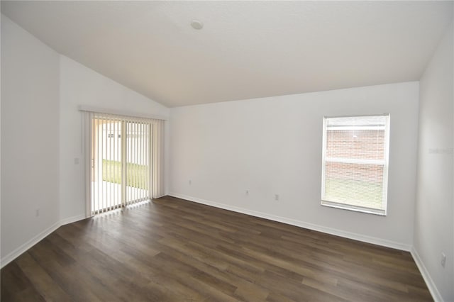 empty room featuring baseboards, vaulted ceiling, and dark wood-type flooring