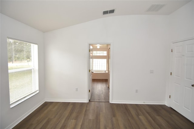 empty room with lofted ceiling, visible vents, dark wood finished floors, and baseboards