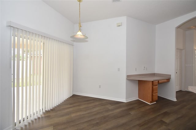 interior space featuring dark wood-style floors, baseboards, arched walkways, and vaulted ceiling