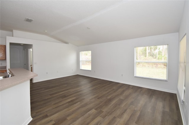 unfurnished living room featuring lofted ceiling, dark wood-type flooring, visible vents, and baseboards