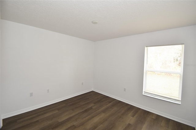 spare room with dark wood-style floors, a textured ceiling, and baseboards