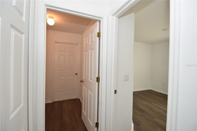 hall with dark wood-style floors and baseboards