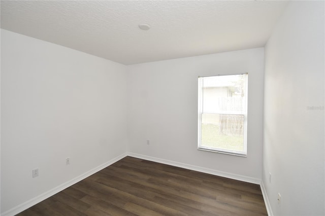 spare room featuring dark wood finished floors, a textured ceiling, and baseboards