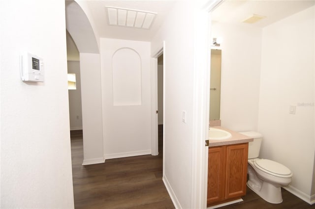 bathroom featuring toilet, wood finished floors, vanity, visible vents, and baseboards