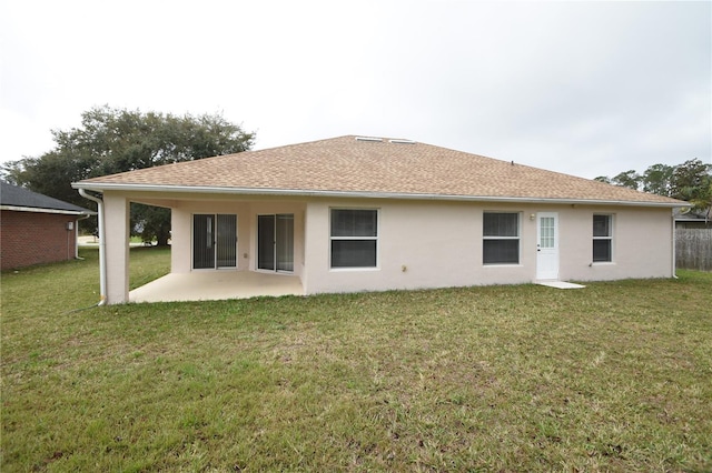 rear view of property featuring stucco siding, roof with shingles, a yard, and a patio