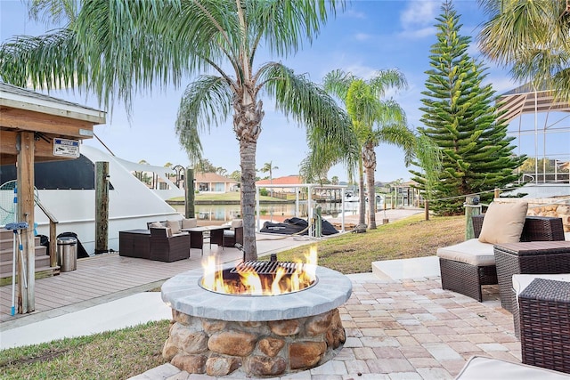 view of patio with a water view and an outdoor living space with a fire pit