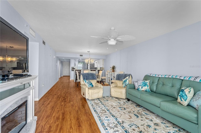 living room with ceiling fan with notable chandelier and wood-type flooring