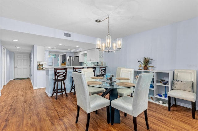 dining space with a chandelier and light wood-type flooring