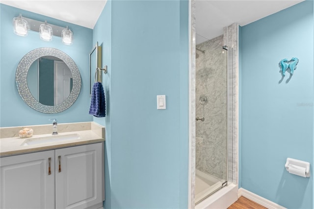 bathroom featuring a shower with door and vanity