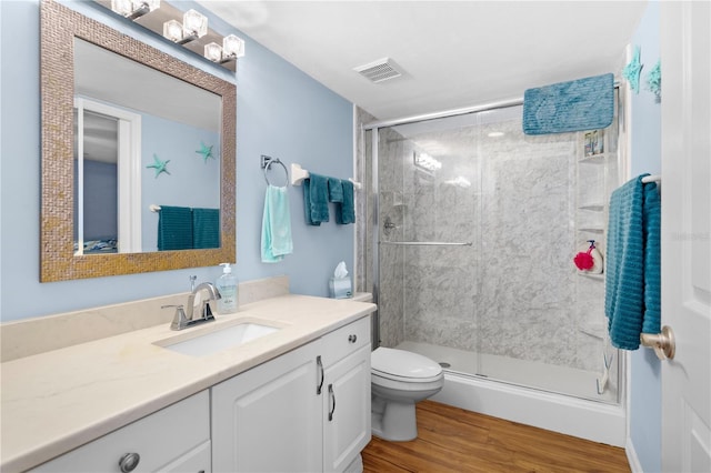 bathroom with an enclosed shower, vanity, hardwood / wood-style flooring, and toilet