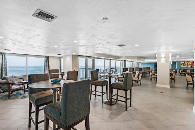 dining room featuring a water view, a wealth of natural light, and a textured ceiling